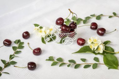 Alışveriş sepeti, olgun kiraz, Yasemin çiçekleri ile arabası, ışık arka plan üzerinde yeşil yeşillik minyatür oyuncak. Sağlıklı gıda, detoks, diyet vitamin, kavramı