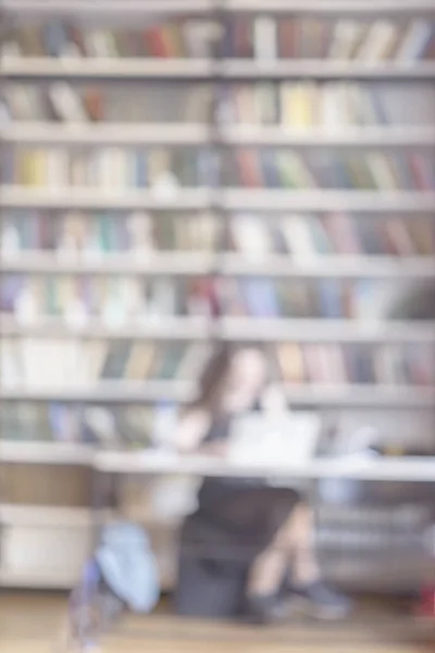 Astratto offuscata ragazza irriconoscibile lettura portatile in biblioteca pubblica, alto armadio, libreria, molti libri, sfondo verticale. Concetto di studing, istruzione — Foto Stock