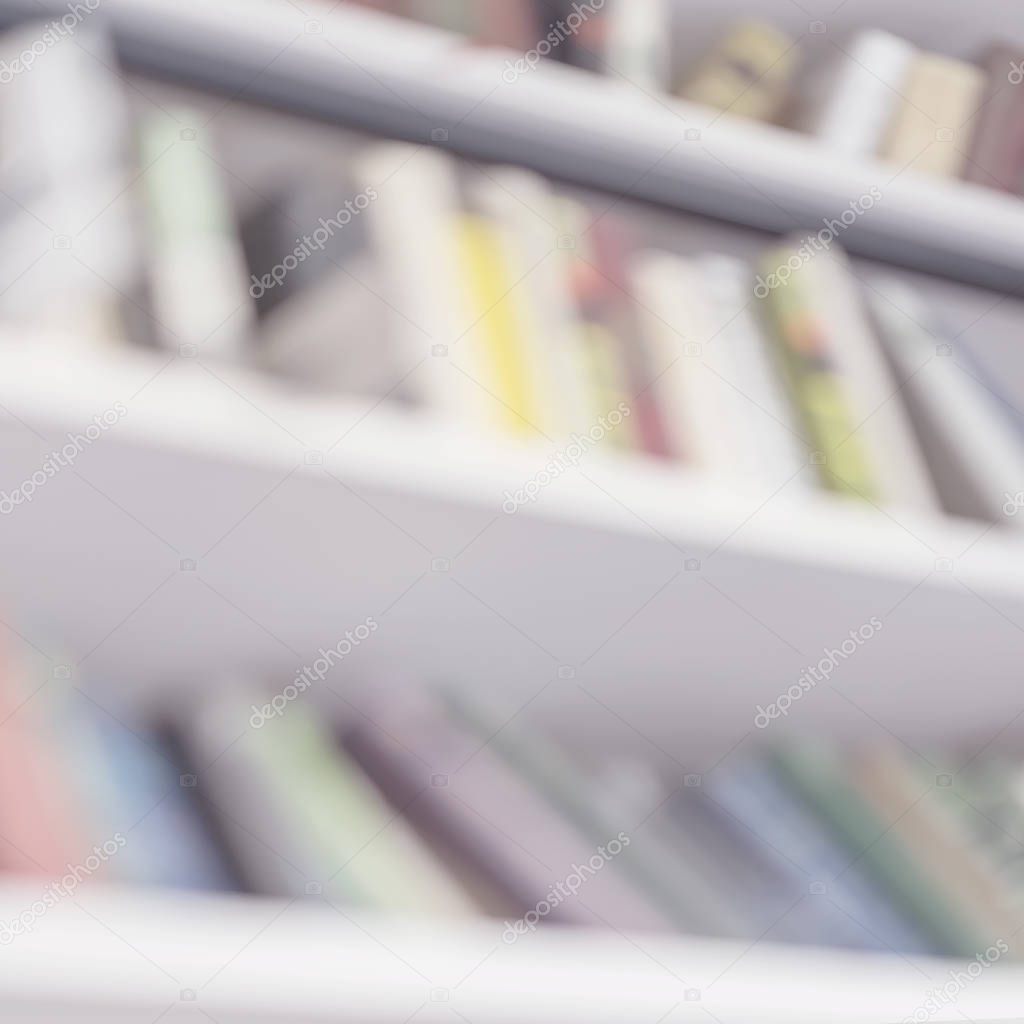 Abstract blurred bookshelves with books in public library, book store, at home, bottom view, modern light square background. Concept of learning, school, education