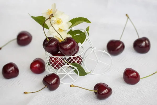 Cereza dulce madura en camión miniatura bicicleta, fondo claro con beryy, flores, hojas. Concepto de alimentación saludable, desintoxicación, vitaminas, dieta, verano — Foto de Stock