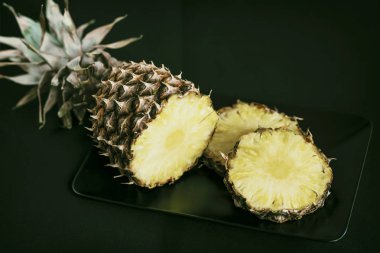 Olgun ve sarı ananas dilimlenmiş siyah saç, koyu arka plan
