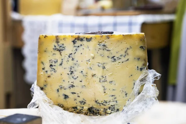 Grande roda de queijo com molde azul no balcão do mercado, cores coloridas. Produtos gastronómicos delicados no balcão do mercado, cena real no mercado alimentar — Fotografia de Stock