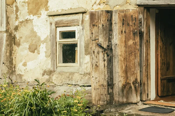 Стена старого фермерского здания. Естественная текстура. Специально сохранившийся сельский деревянный дом для агротуризма, окна, открытая дверь, загородный дом. Лето, цветы во дворе — стоковое фото