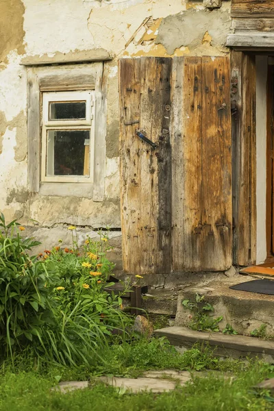 Стіна старої фермерської будівлі. Натуральна текстура. Спеціально збережений сільський дерев'яний будинок для агатизму, вікна, відкриті двері, заміський старовинний будинок. Літо, квіти у дворі — стокове фото