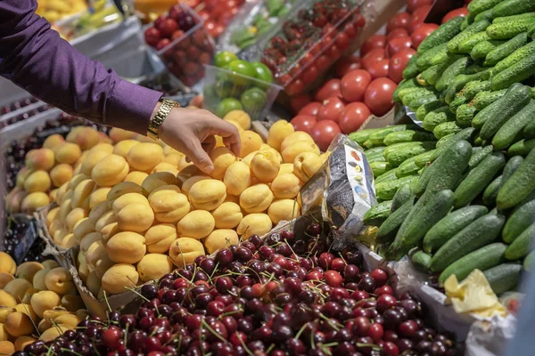 Мужская рука держит над прилавком со свежими фруктами крупным планом на продовольственном рынке — стоковое фото