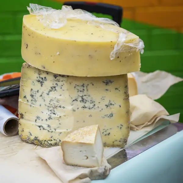 Grandes pedaços de queijo com mofo azul no balcão do mercado. Produtos gastronómicos delicados no balcão do mercado, cena real no mercado alimentar — Fotografia de Stock