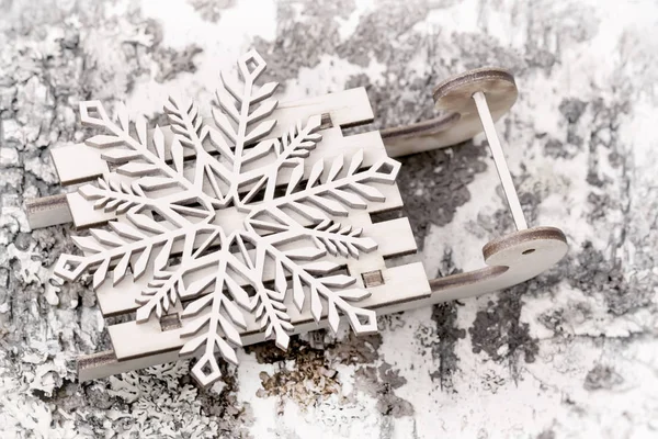 Decoração de madeira, floco de neve em pouco de madeira trenó close-up. Abstrato desfocado luz festiva fundo de Natal . — Fotografia de Stock