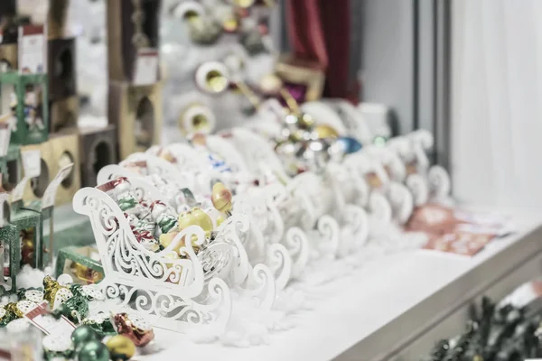 Schmuck, Weihnachtskugeln und weiße Holzschlitten. Verkauf von Weihnachtsdekorationen. abstraktes Licht verschwimmt Urlaubshintergrund. — Stockfoto