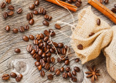 Kavrulmuş kahve çekirdekleri çuval bezi kumaş eski yıpranmış ahşap ve baharatlar ile. antika arka plan kullanın. Üstten görünüm. Metin için yer