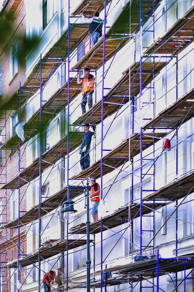 Construction d'un nouveau bâtiment résidentiel urbain de grande hauteur, travailleurs sur différents étages, échafaudage de mur de façade — Photo