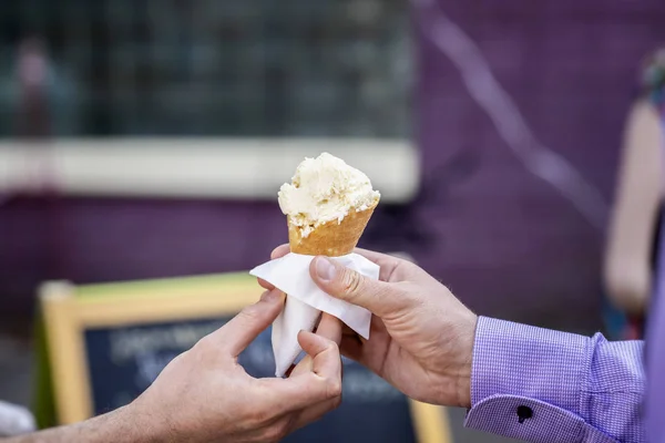 Waffle cone with ice cream, two hands are drawn to summer pleasure. Background with colorful bokeh. Real scene in the store