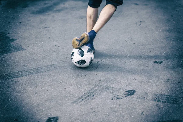 Legs, feet of football player, dribbling with the ball on asphalt in yard
