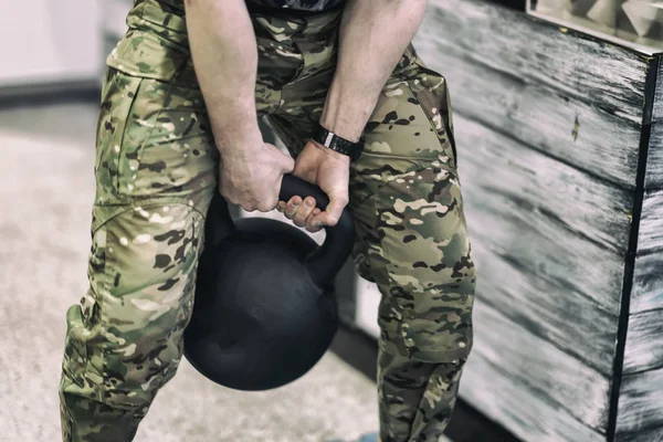 Abstract athlete in camouflage pants with weights, lifting a heavy weight