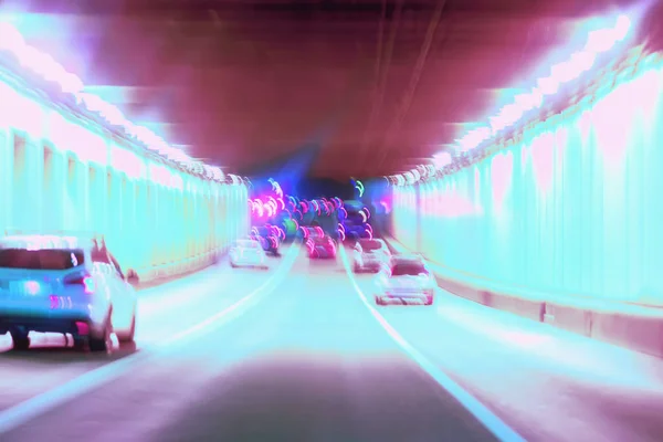 Abstract blurred driving in the tunnel at night, moving cars, urban street illumination. Concept of modern lifestyle of the city at night