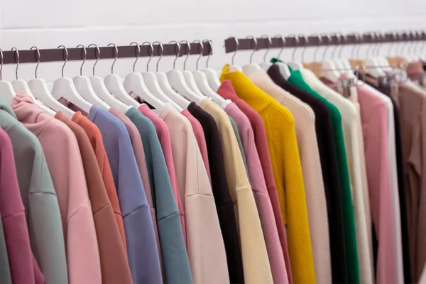 Coloridos suéteres y sudaderas con capucha de cachemira juvenil, sudaderas y en un estante de ropa en la tienda — Foto de Stock