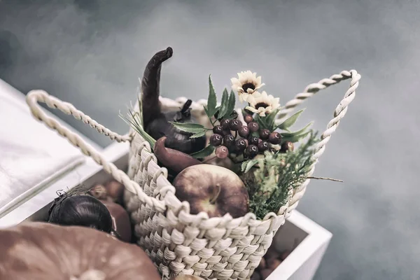 Home festive flower arrangement from leaves, flowers, vegetables, fruits, berries in the rustic wicker basket. Autumn holidays — Stock Photo, Image