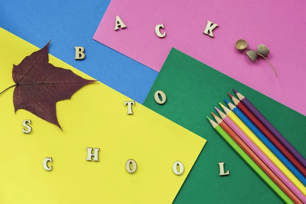Lápices de colores, hojas de arce y texto de regreso a la escuela, letras de madera en hojas de papel de colores. Concepto de educación, inicio de la escuela —  Fotos de Stock