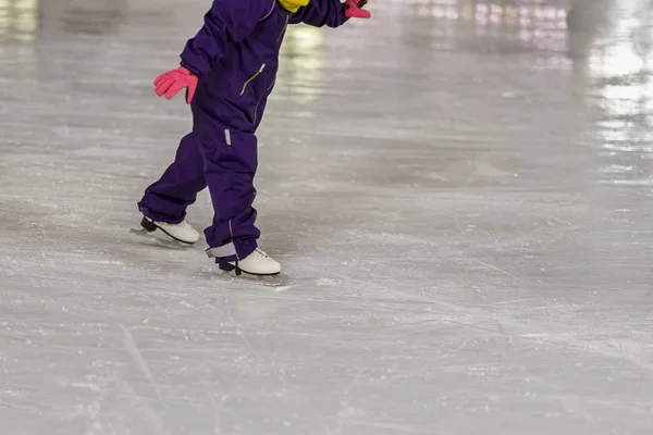 Small child in overalls learn to skate outdoors at the rink in the winter park — Stock Photo, Image