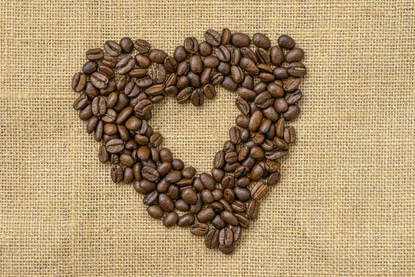 Heart coffee. Roasted coffee beans in the shape of heart on natural canvas, sackcloth. Concept of coffee love or a loved one