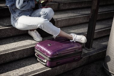 Tanınmayan genç kız öğrenci bir bavul, gençlik seyahat ve turizm konsepti ile merdivenlerde oturan