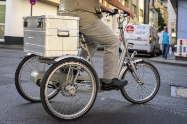 Yük taşımak için arka gövdeleri olan yetişkinler için üç tekerlekli bisikletüzerinde tanınmayan adam binmek, paketlerin teslim hizmeti