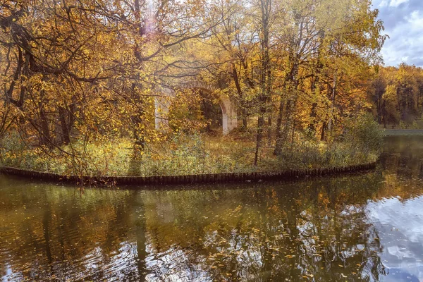 Мальовничий осінній пейзаж, стара зруйнована кам'яна арка на острові з лісом і річкою, барвисте яскраве листя дерев, сонячний день — стокове фото