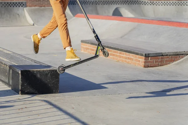 Nohy v tenisky teenager skákání kop skútr v skate parku. Pouliční kultura mladého, aktivního životního stylu — Stock fotografie