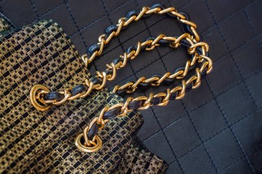 Akşamları, koyu arkaplanda parlak zincirleri olan altın sarısı siyah el çantası, üst manzara, düz yatış. Logo yok, isim yok. Alışveriş konsepti.