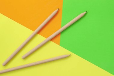 Parlak renkli arka planda üç basit kalem, düz bir zemin. Okula ve eğitim konseptine dönüş