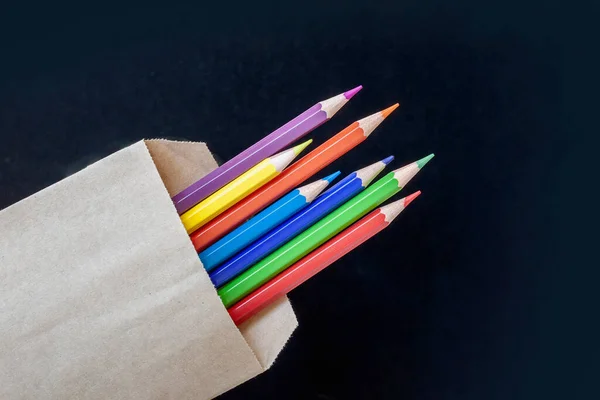 Wielokolorowe ołówki w torbie na czarnym tle — Zdjęcie stockowe