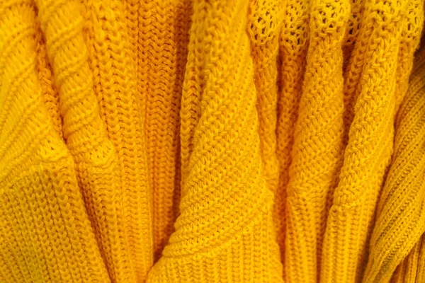 Kilka dzianych ciepłych żółtych pulowerów o różnych wzorach waży na wieszaku. — Zdjęcie stockowe
