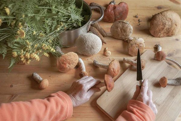 Setas de bosque fresco en una tabla de madera, mesa, manos femeninas con un cuchillo, comida para cocinar, vista superior —  Fotos de Stock