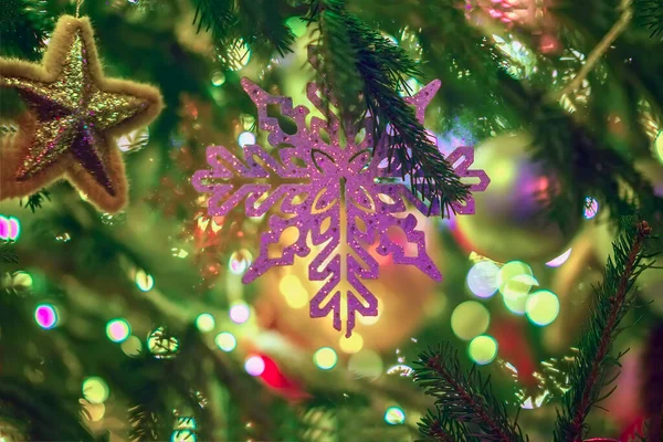 Pohon Natal dengan dekorasi neon, bintang Natal, kepingan salju, bola, karangan bunga. Fokus selektif. Latar belakang meriah abstrak. — Stok Foto