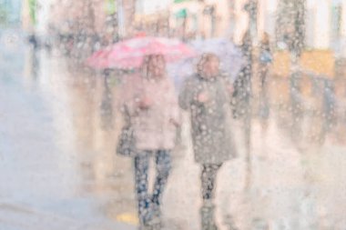 Açık renkli arka planda bulanık iki kız silueti yağmurlu bir günde şemsiye altında kız arkadaşlar, şehir hayatı, bokeh. Modern şehir yaşam tarzı kavramı.