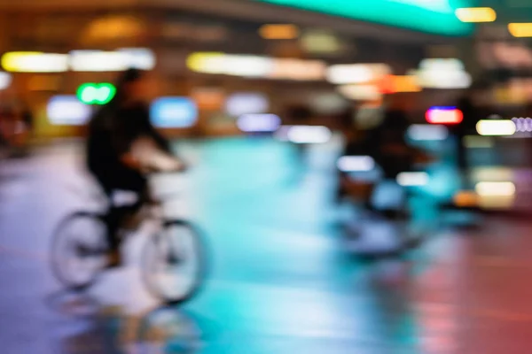 Wazig stijl achtergrond van silhouet van abstracte onherkenbare man, paardrijden fiets, nacht stad, verlichting bokeh, bewegingsvervaging. Gezonde levensstijl, concept van vrijetijdsbesteding. — Stockfoto