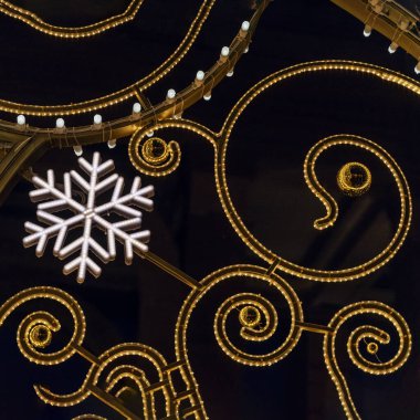 Metalik beyaz, parlak parlak kar taneleri yakın plan, gece kentinde siluet, bayram sembolü.