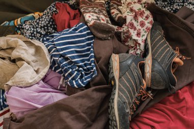 Karışık giysi yığını ve kullanılmış ayakkabılar tekstil atıklarını ve geri dönüşüm sorunlarını sembolize ediyor. Sıfır atık kavramı, sürdürülebilir yaşam, dairesel moda