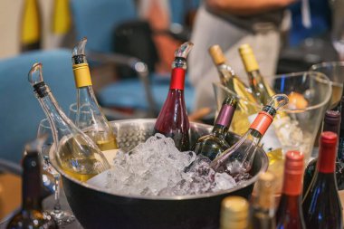 Chilled wine bottles in ice buckets prepared for tasting event, showcasing red and white wine selection in elegant setting. Concept of wine tasting, celebration, luxury lifestyle