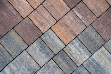 Renkli kaldırım taşları düzgün çapraz dizilmiş sıcak kahverengi ve serin gri renkler arasındaki kontrastı gösteriyor. Asfalt, doku, inşaat arka planı kavramı