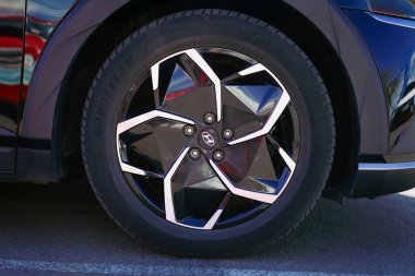 BURGAS, Bulgaria - September 20, 2025: Black alloy wheel features striking geometric design on contemporary SUV parked in vibrant urban setting