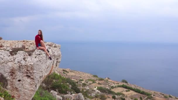 石崖ディングリ マルタ北部地域で有名な自然ランドマークの上に座っている女の子 — ストック動画