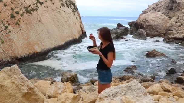 Giovane Ragazza Pranza Sullo Sfondo Del Mare Scogliere Sull Isola — Video Stock