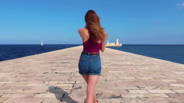 女の子は海の真ん中でさびれた道を歩きます マルタ バレッタ — ストック動画