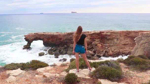 Flickan Ser Vågorna Som Slår Stone Arch Vackra Naturliga Klippformationer — Stockvideo