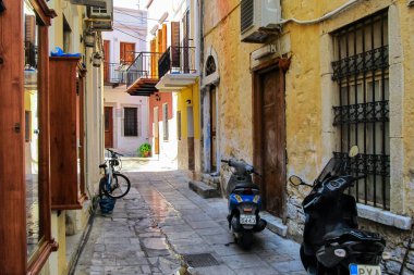 Symi, Yunanistan - 4 Ekim 2014: Popüler ulaşıma sahip Symi adasının dar caddesi - bir motosiklet