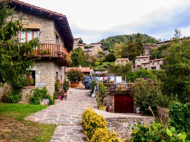 Rupit Pruit, Katalonya, İspanya - 8 Ekim 2013: Dağlardaki bir ortaçağ kasabasında antik mimarinin yerleşim binaları. Kırsal hayatın elementleri (sokakta kurutma giysileri, ön bahçe)