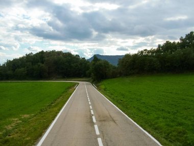 Tepeler ve alacakaranlıkta yeşil tarlalar arasında yol
