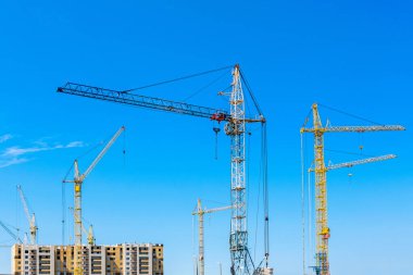Mavi gökyüzüne karşı inşaat vinçleri
