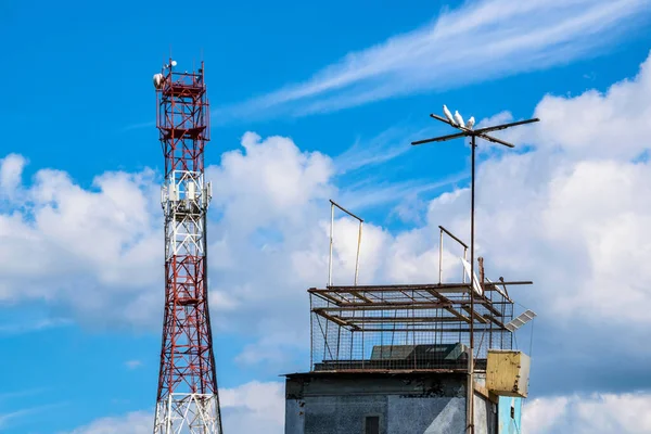 Dovecote and telecommunication cell tower against colorful sky background