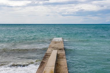 Denize açılan beton bir iskele. Işık dalgaları, bulutlu hava